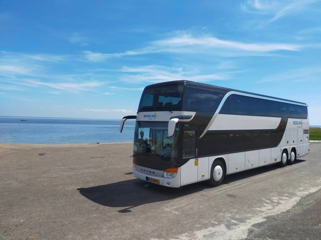 Dubbeldekker touringcar van Besseling Travel geparkeerd aan zee
